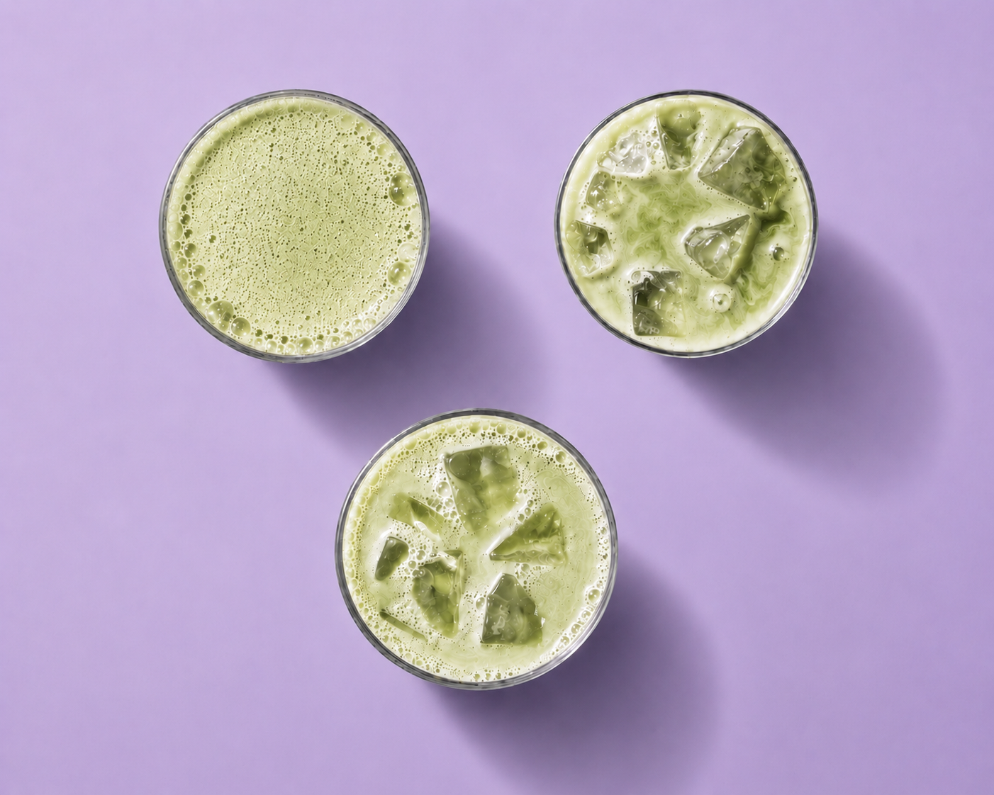 Three glasses of green smoothies on a purple background