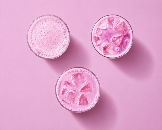 Three pink drinks with ice cubes on a pink background
