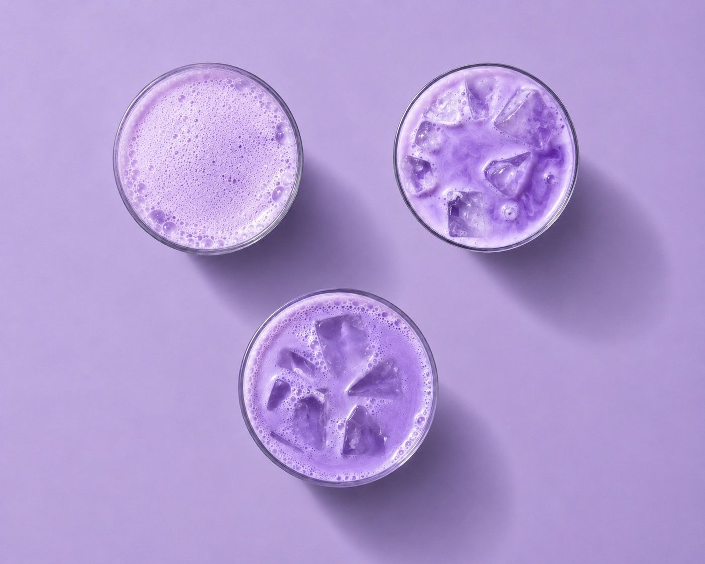 Three glasses of purple iced drinks on a purple background
